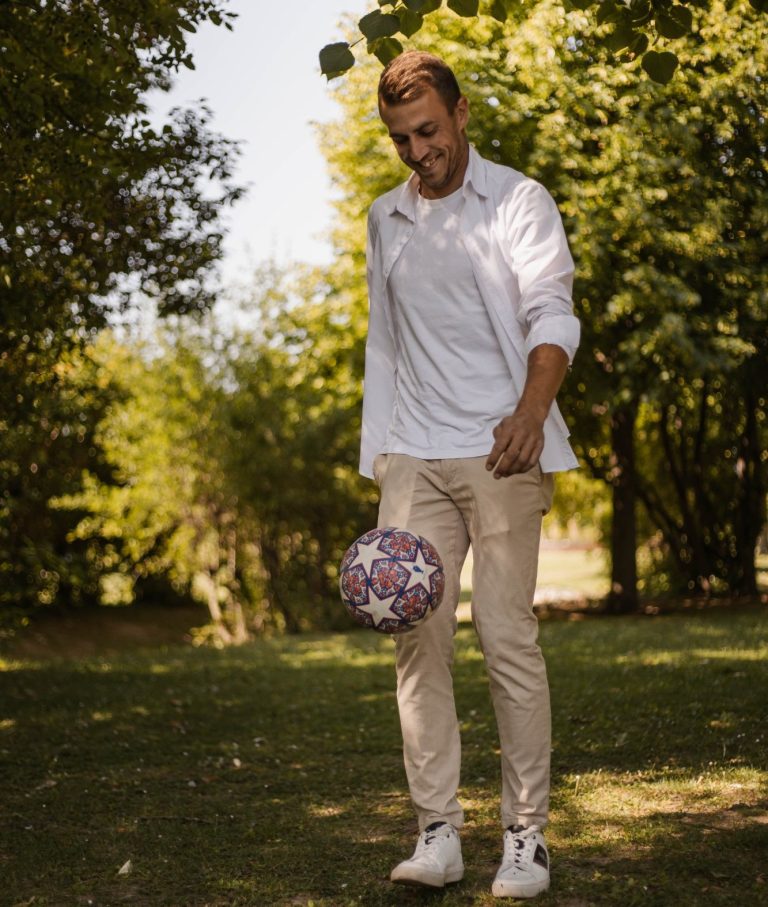 Benjamin Feurer im Freien spielt mit einem bunten Fußball auf einer Wiese.